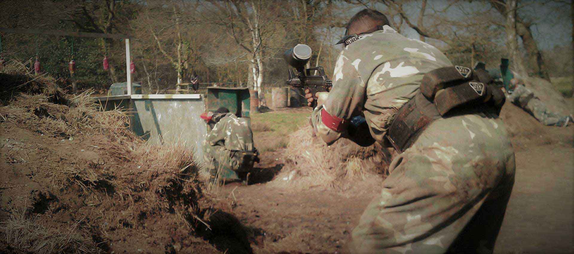 Paintball battle wages as men run forwards attacking the opposing team.