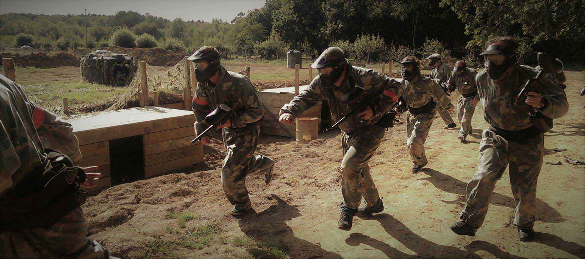 Members of the red team run as they storm a trench system with their paintball guns.