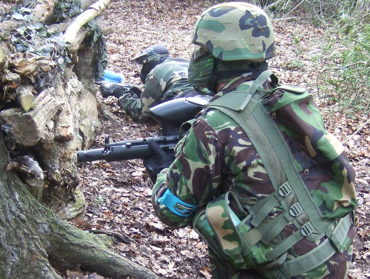 Two teammates take cover from incoming paintballs whilst preparing an assault.