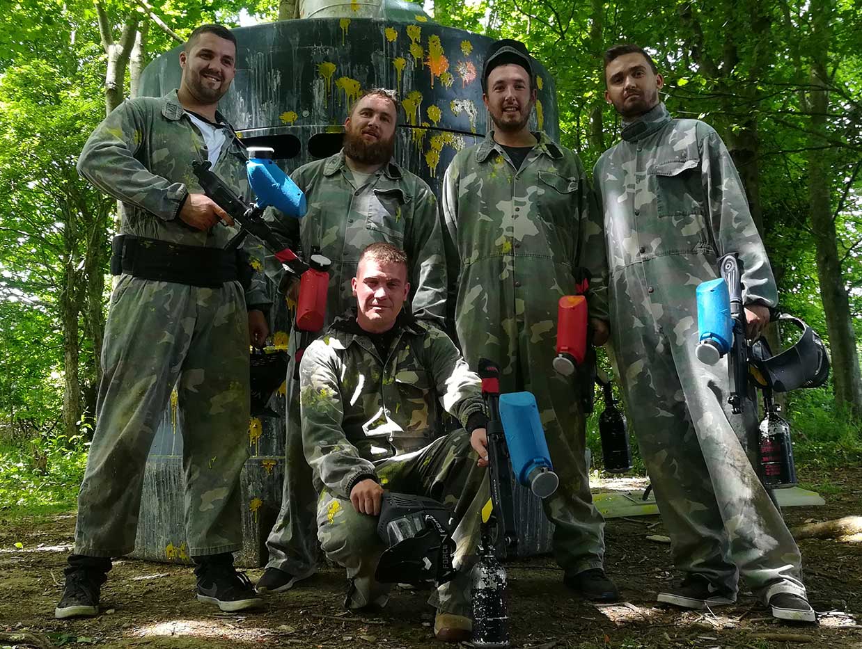 Group of men on a stag do posing for a photo after a fun day of paintballing.