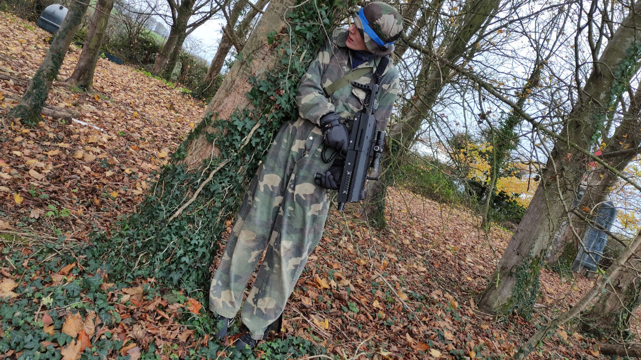 Player taking cover behind a tree blending in with her woodland surroundings.