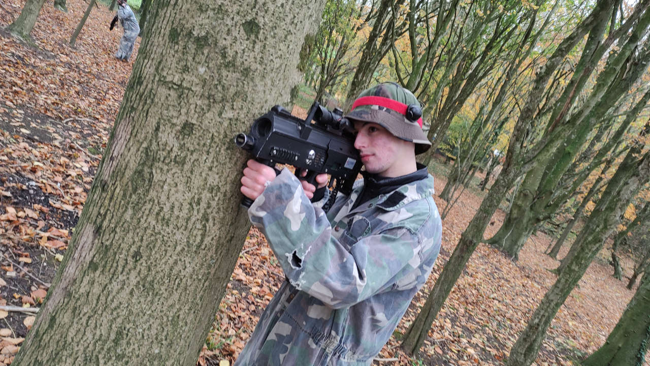 Player aiming his laser tag gun in the woods.