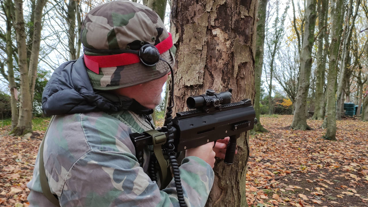 A member of the red team takes cover behind a tree during laser combat.