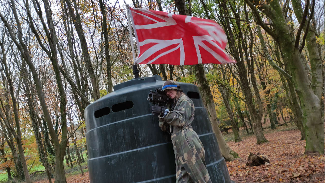 Red Team base camp with battle flag, the base is guarded by a female player.